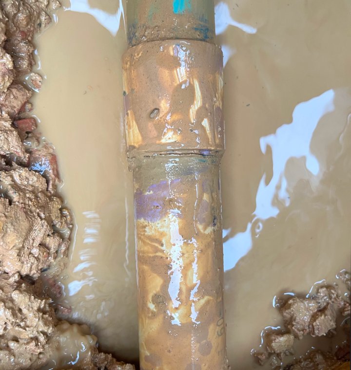 A dirty, freshly unearthed pvc pipe in dirty water